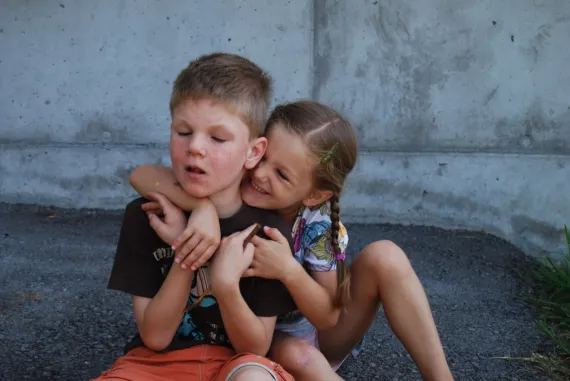 Mädchen umarmt ihren kranken Bruder. Titel Geschwisterliebe. 