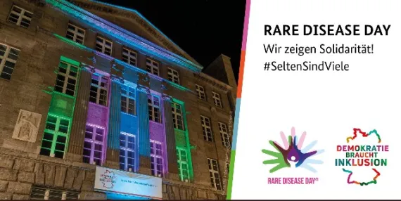 Häuserfassade bunt angestrahlt. Daneben Logo vom Rare Disease Day und vom Behindertenbauftragten der Bundesregierung. Im Text steht Rare Disease Day Wir zeigen Solidarität. #SeltensindViele