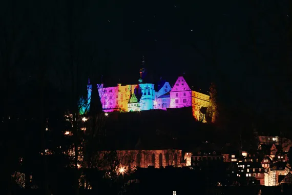 Bunt beleuchtete Burg auf Berg in Dunkelheit. 