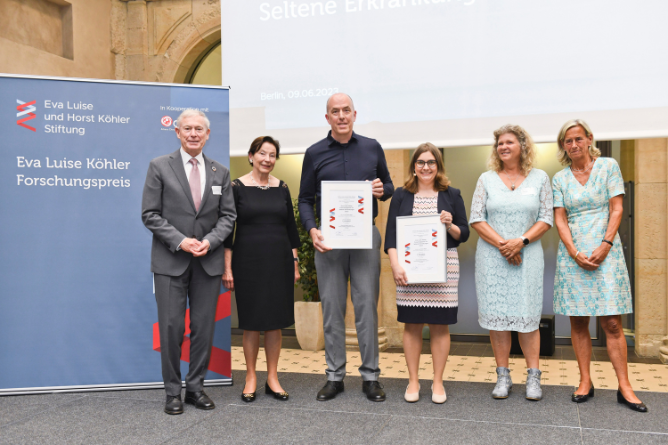 Prof. Dr. Horst und Eva Luise Köhler, die Preisträger Dr. Axel Lankenau und Dr. Simone Mayer, Geske Wehr (ACHSE e.V.) und Prof. Dr. Annette Grüters-Kieslich, Vorstandsvorsitzende Eva Luise und Horst Köhler Stiftung (von links) Sechs Personen stehen nebeneinander in einem Saal, zwei halten Urkunden, links steht ein blauer Banner mit der Aufschrift 'Eva Luise Köhler Forschungspreis'