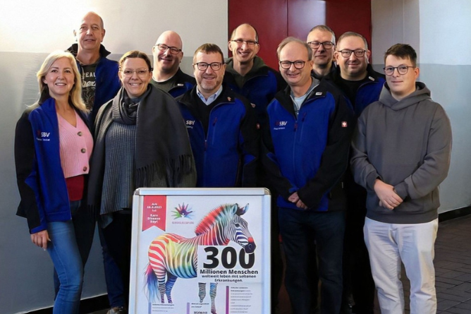 Gruppe von Menschen steht hinter einem Plakat mit einem bunten Zebra und der Zahl '300'