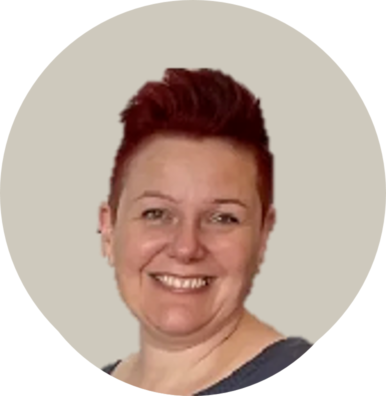 Frau mit kurzen, rotbraunen Haaren, trägt dunkles Oberteil, vor hellem Hintergrund