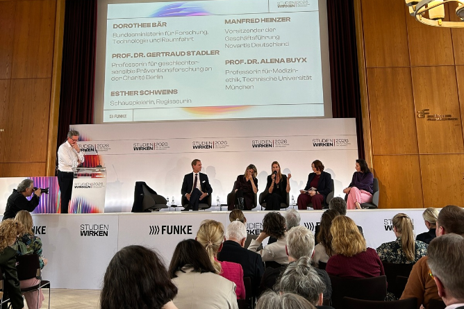 Podiumsdiskussion bei STUDIEN WIRKEN 2026 Fünf Personen sitzen auf einer Bühne vor einem Publikum, im Hintergrund eine Leinwand mit Text zu Vortragenden und Veranstaltern.