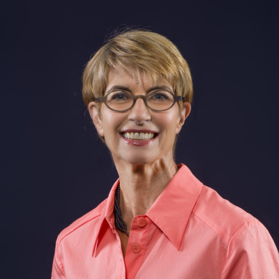 Freundlich Frau mit kurzen blonden Haaren und Brille in einer rosa Bluse