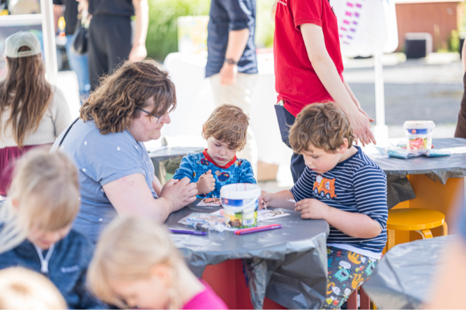 © Ravensburger Spieleland 2026 Kinder sitzen an einem Tisch und basteln mit verschiedenen Materialien im Freien